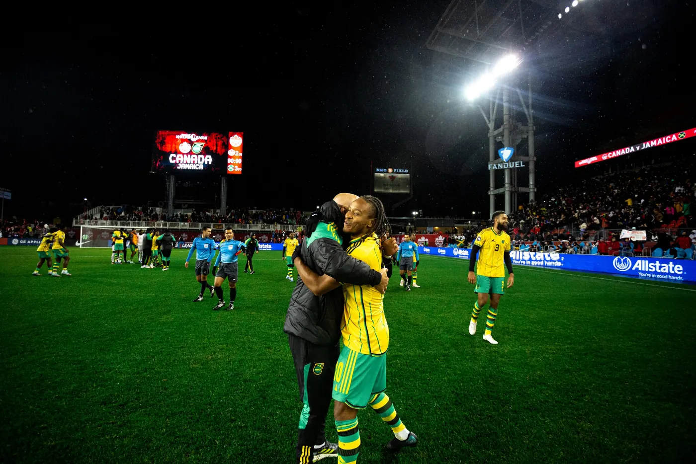 John Wall embracing a Jamaica player on the pitch after a Concacaf Nations League match at night in Toronto