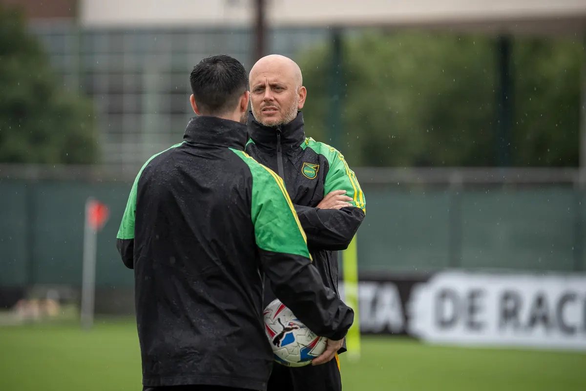 John Wall in conversation with a Jamaica colleague during a rainy training session