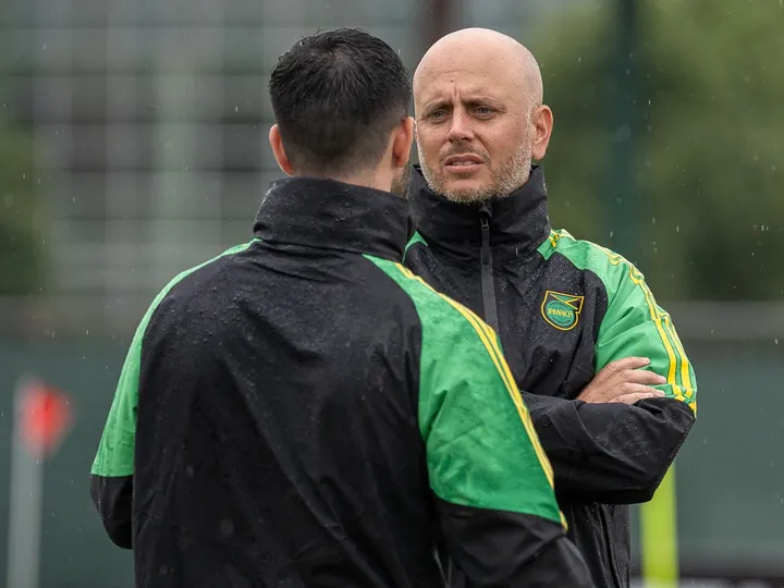 John Wall in conversation with a Jamaica colleague at a rainy training session